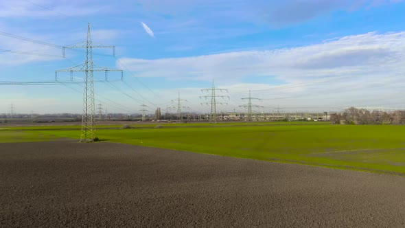 Drone video of a flight along a power line towards a substation during daytime on a clear day