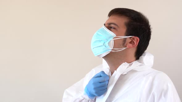 Doctor in white PPE suit putting on hood