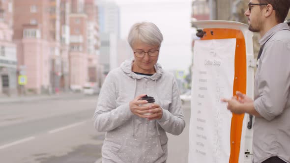 Senior Mixed Race Lady Buying Coffee from Street Van and Drinking