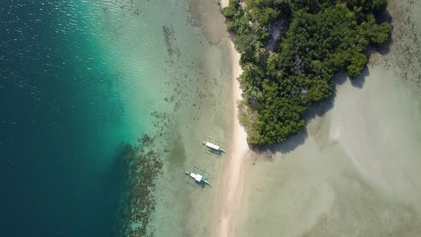 Aerial view of long sandbar and island with vegetation and mangrove surrounded by beautiful clear wa