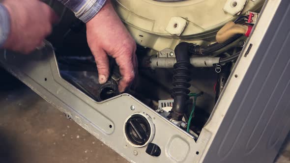 The Hands of the Foreman Disconnect the Tubes Inside the Washing Machine