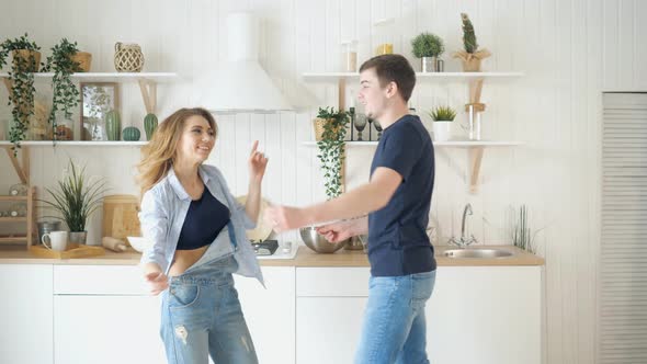 Happy Young Couple Dancing in Kitchen Wearing Jeans Dance