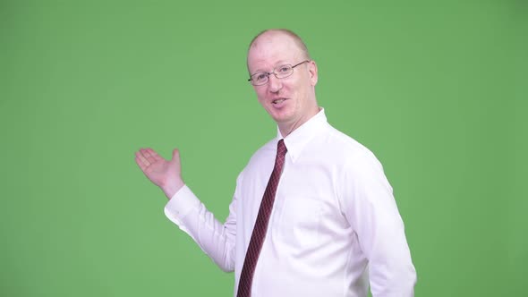 Mature Bald Businessman Presenting Something