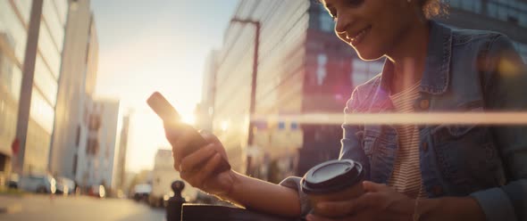 Video of smiling Brazilian woman sitting with mobile phone outdoors.