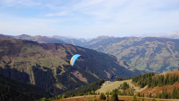 Paragliding - Tourists Fly In The Sky With A Colorful Parachute Over Mount Schmitten In Austria. aer