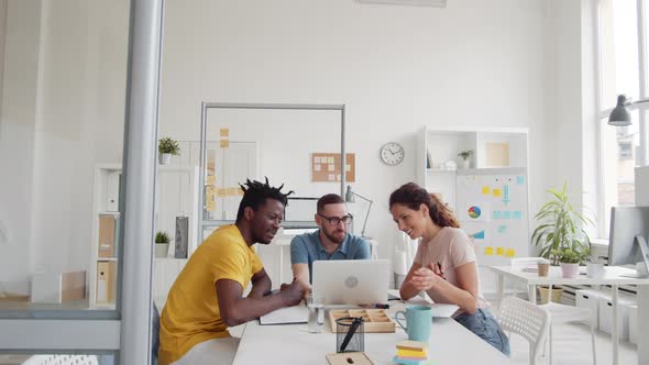 Three Colleagues Using Laptop in Office