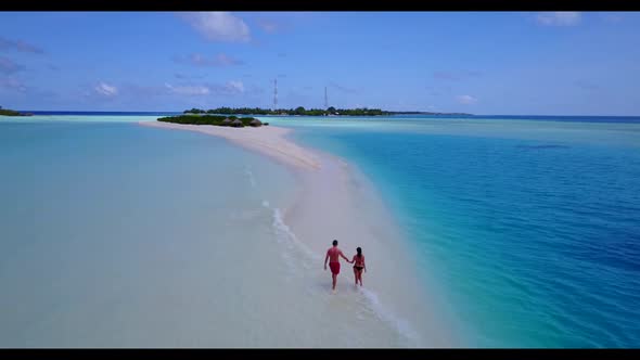 Guy and girl engaged on tranquil resort beach journey by aqua blue sea with white sand background of