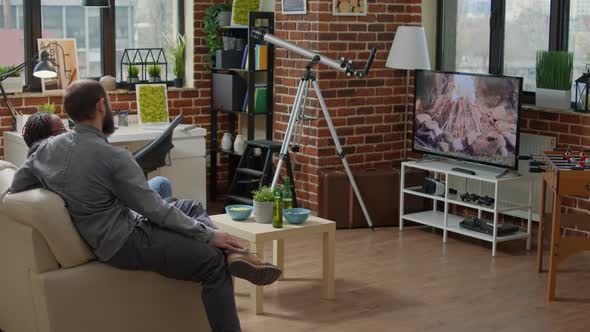 Diverse Group of People Sitting Together and Watching Film on TV