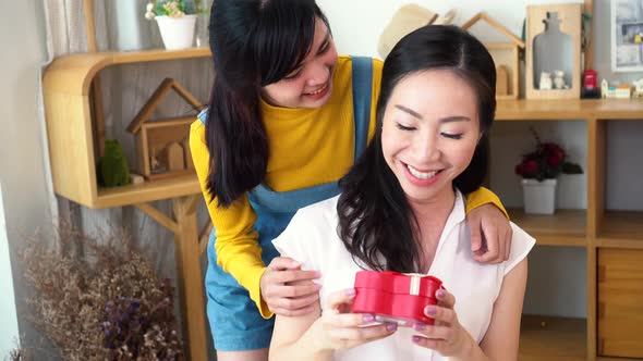 Smiling Happy Asian Teenage Daughter and Mother Hugging Together in Indoor Living Room at Home