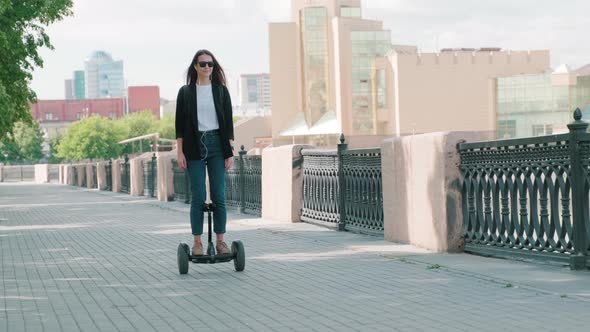 Woman Walking Along Bridge On Gyroscooter