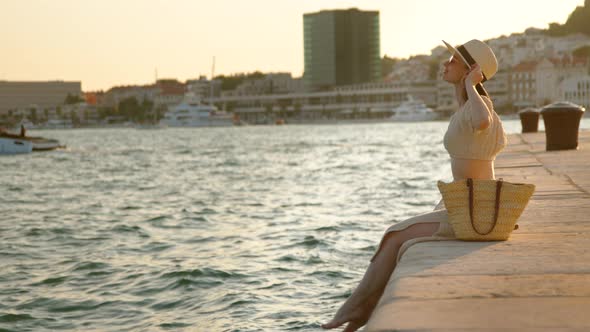 Happy woman with bare feet on the pier in summer. Split, Croatia