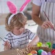 charming woman and her two-year-old son in bunny ears paint Easter eggs with paints - VideoHive Item for Sale