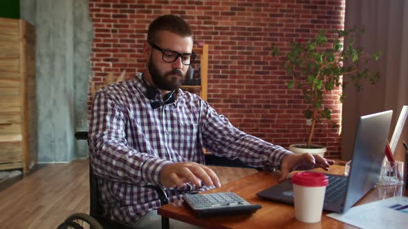 Businessman with Glasses in Wheelchair Conducts Budget Calculations