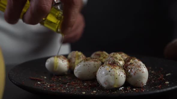 An Ilalian Chef Pours Yellow Olive Oil Over Mozzarella, Cheese in Spices.