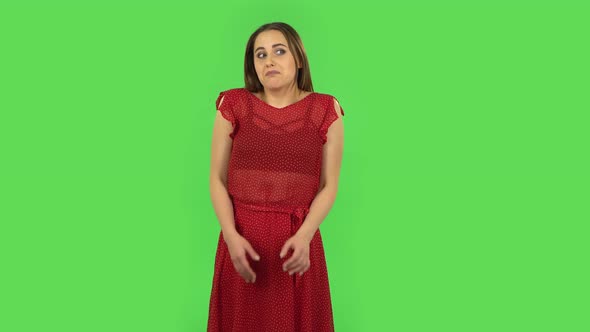 Tender Girl in Red Dress Is Saying Oops and Shrugging and Biting Lips. Green Screen