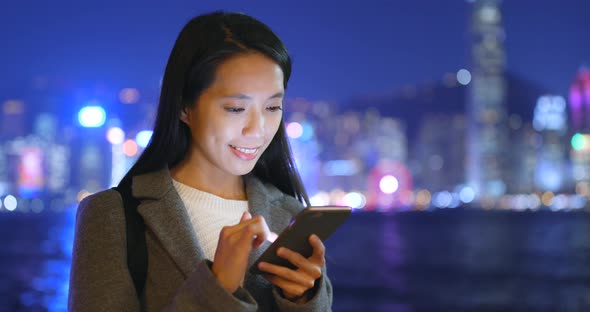 Businesswoman use of mobile phone in Hong Kong at night