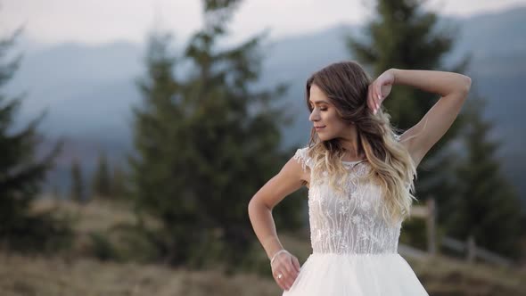 Beautiful Lovely Stylish Bride in White Wedding Dress Waiting for Groom on Mountain Slope Hill