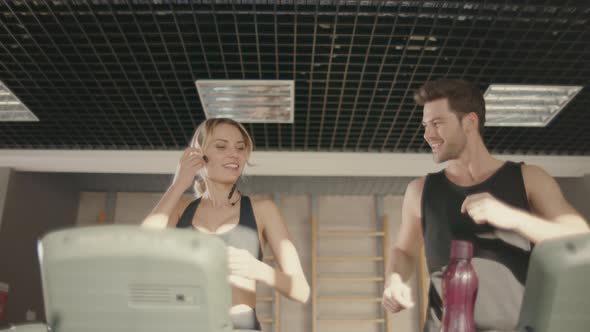 Joyful Fitness Couple Talking on Treadmill Machine in Gym Club