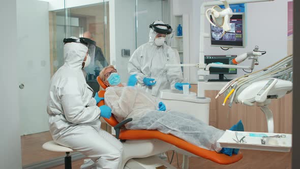 Dental Specialist with Coverall Talking with Patient Before Examination