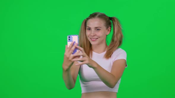 Beautiful Caucasian Female Takes a Selfie on a Smartphone Young Woman Takes Pictures of Herself on a