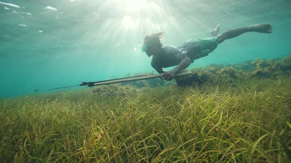 Beautiful Underwater Scene of a Man Spearfisher Swimming Near Sea Grasses