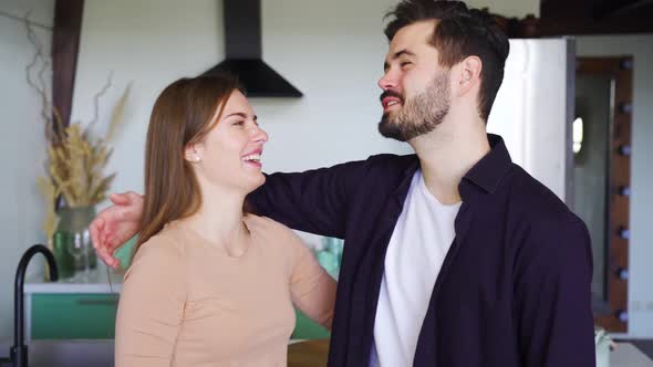 Young Happy Family Couple Standing at Home Kitchen and Talking Planning Future