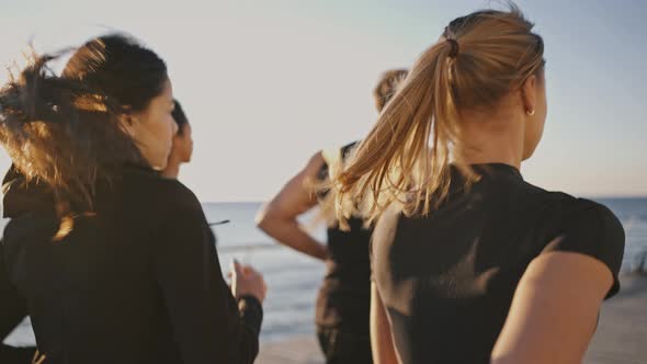 Group of Young Sporty People Practicing Morning Run at Seaside Jogging Together on Pier in Morning