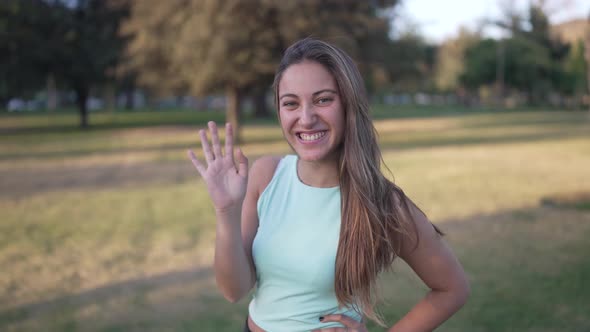 a Cute White Girl Waves to the Front and Making a Symbol of Love and Peace