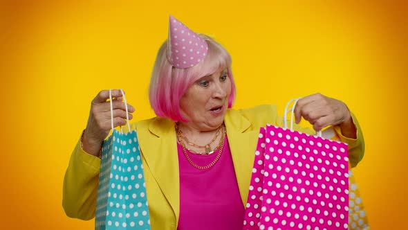 Elderly Granny Woman Showing Shopping Bags Advertising Discounts Looking Amazed with Low Prices