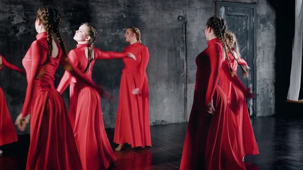Modern Ballet Performed By Seven Dancers. Girls in Red Dresses Synchronously Perform Dance Elements