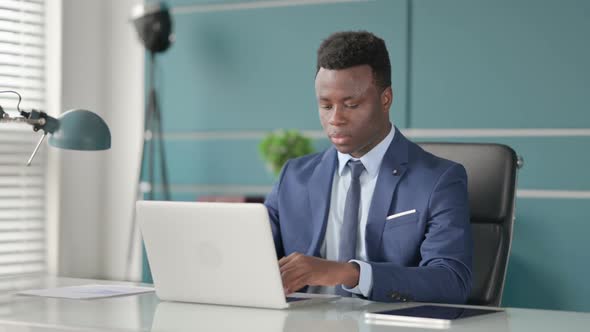 African Businessman Coughing While Using Laptop in Office