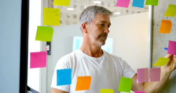Male Executive Writing on Sticky Note on Glass Wall 4k