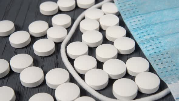 Medical protective mask and pills close-up on a gray wooden surface.