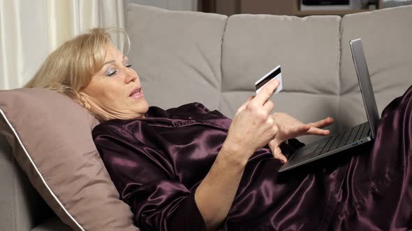 Middle Aged Woman Pays for Purchases Online Via Laptop
