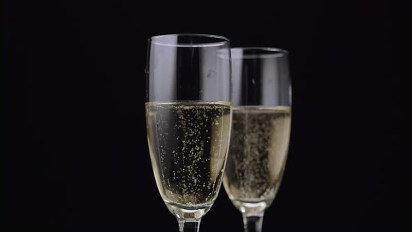 Two Glass of Champagne with a Rotating Bubbles Inside. Black Background. Close Up