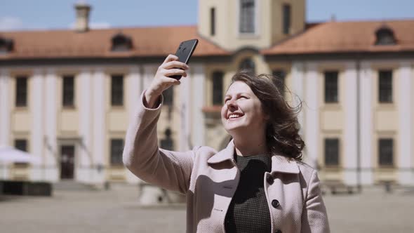 Happy Woman with Freckles Takes Photo on Smartphone of Medieval Castle