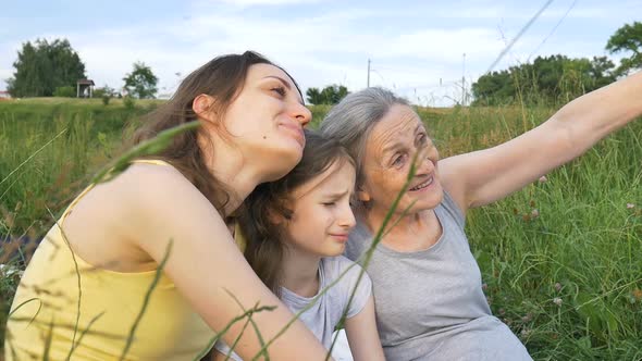 Cute Child Girl with Her Young Mother and Senior Grandmother are Having Picnic During Summer Outdoor