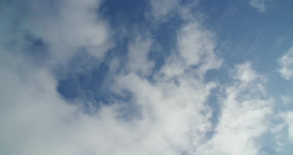 Time-lapse looking straight up as clouds race by overhead. Gradually a second, higher layer of cloud