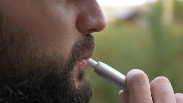 The Bearded Man Smokes an Electronic Cigarette
