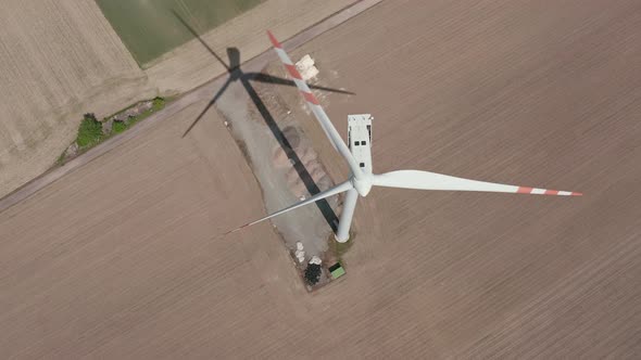 Aerial Reveal Of A Huge Wind Turbine Generating Renewable Energy In The Farm On A Sunny Day. overhea