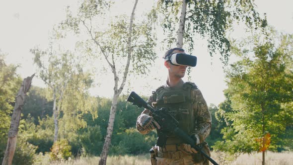 Soldier with Rifle Wearing Virtual Reality Glasses Outdoors