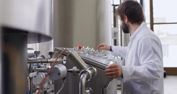 A Male Brewer with a Beard at Brewery Factory Working Behind the Control Panel Dashboard