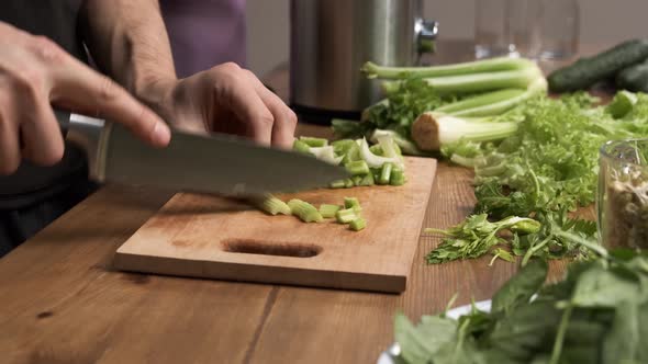Making Green Juice at Home Male Hands Cut Celery with a Knife on a Board Table in the Kitchen
