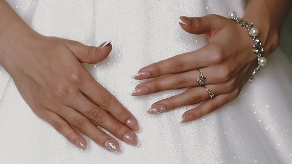 Bride in Shining Dress Shows Hands with Rings and Bracelet