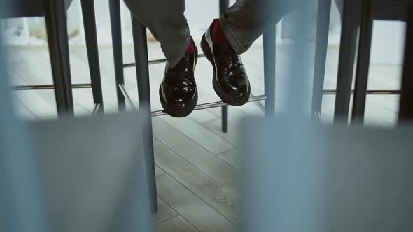 Lonely Man Keeping Distance Moves Feet in Shoes While Sitting on Bar Stool