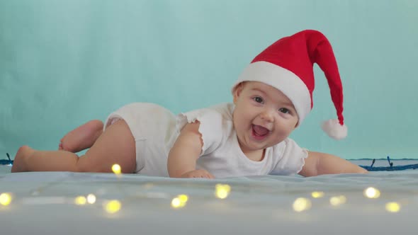 Funny Little Baby Smiling, Cute Infant Boy Wearing Santa Hat Lying on Sofa