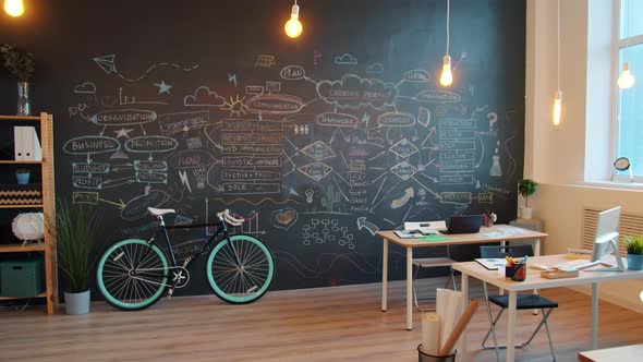 Zoom-out of Modern Creative Office with Blackboard Wall and Desks with No People