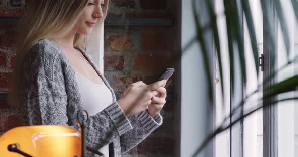 Caucasian woman using her phone in her house