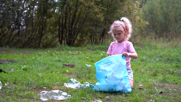 a Little Girl Removes Plastic Garbage and Puts It in a Biodegradable Garbage Bag Outdoors