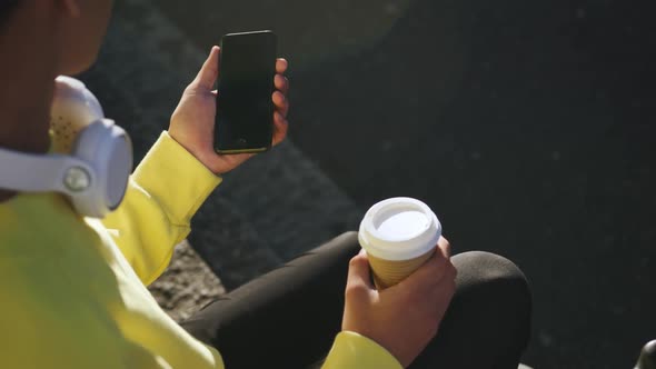 Transgender adult with coffee using a phone